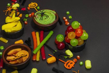 Cadılar Bayramı partisi için geleneksel festival kompozisyonu. Tatlı mevsimlik yemekler, ev yapımı sonbahar dekorasyonu. Sert ışık, karanlık gölge, siyah taş beton zemin, düz zemin, kopyalama alanı