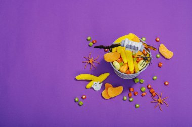 Cadılar Bayramı partisi için geleneksel festival kompozisyonu. Tatlı mevsimlik yemekler, ev yapımı sonbahar dekorasyonu. Sert ışık, koyu gölge, mor arkaplan, düz yatış, üst manzara