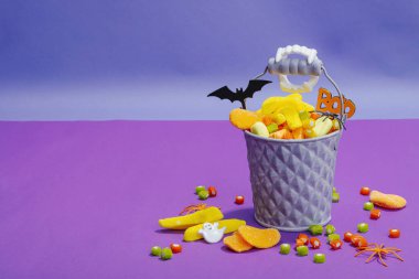 Cadılar Bayramı partisi için geleneksel festival kompozisyonu. Tatlı mevsimlik yemekler, ev yapımı sonbahar dekorasyonu. Sert ışık, koyu gölge, mor arkaplan, düz yatış, kopyalama alanı