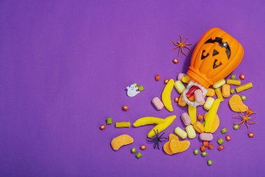 Cadılar Bayramı partisi için geleneksel festival kompozisyonu. Tatlı mevsimlik yemekler, ev yapımı sonbahar dekorasyonu. Sert ışık, koyu gölge, mor arkaplan, düz yatış, üst manzara
