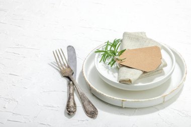 Minimalist masa düzeni. Zarif çatal bıçak takımı, geleneksel sıfır atık malzemesi, düz döşeme. Keyifli bir ortam, boş tabaklar. Sert ışık, koyu gölge, beyaz macun arkaplanı, kopyalama alanı