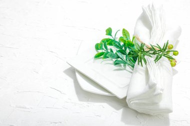 Minimalist masa düzeni. Zarif çatal bıçak takımı, geleneksel sıfır atık malzemesi, düz döşeme. Keyifli bir ortam, boş tabaklar. Sert ışık, koyu gölge, beyaz macun arkaplanı, kopyalama alanı