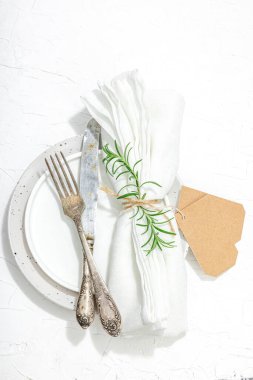 Minimalist masa düzeni. Zarif çatal bıçak takımı, geleneksel sıfır atık malzemesi, düz döşeme. Keyifli bir ortam, boş tabaklar. Sert ışık, koyu gölge, beyaz macun arkaplan, üst görünüm