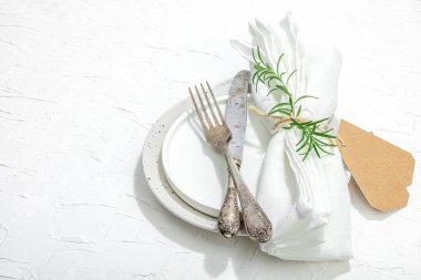 Minimalist masa düzeni. Zarif çatal bıçak takımı, geleneksel sıfır atık malzemesi, düz döşeme. Keyifli bir ortam, boş tabaklar. Sert ışık, koyu gölge, beyaz macun arkaplanı, kopyalama alanı