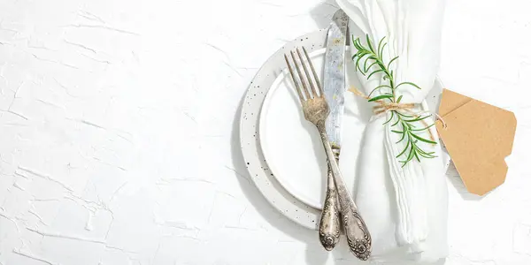 Minimalist table setting. Elegant cutlery, traditional zero waste props, flat lay. Festive cozy mood, empty dishes. Hard light, dark shadow, white putty background, banner format