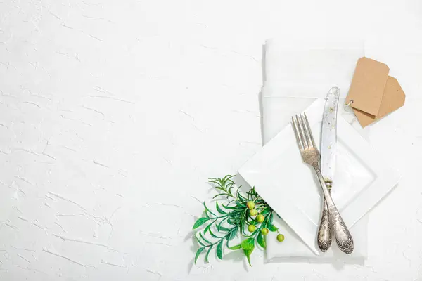 Minimalist table setting. Elegant cutlery, traditional zero waste props, flat lay. Festive cozy mood, empty dishes. Hard light, dark shadow, white putty background, top view