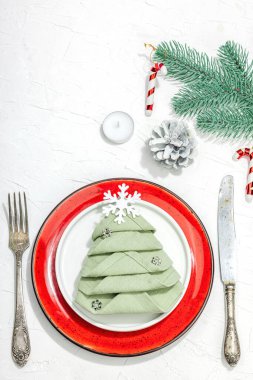 Noel sofrası. Yeni yıl çatal bıçak takımı, geleneksel kış dekorasyonu, düz yatak. Keyifli bir ortam, minimalist tasarım. Sert ışık, koyu gölge, beyaz macun arkaplan, üst görünüm