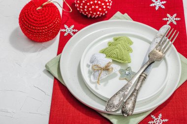 Noel sofrası. Yeni yıl çatal bıçak takımı, geleneksel kış dekorasyonu, düz yatak. Keyifli bir ortam, minimalist tasarım. Sert ışık, koyu gölge, beyaz macun arkaplanı, kopyalama alanı