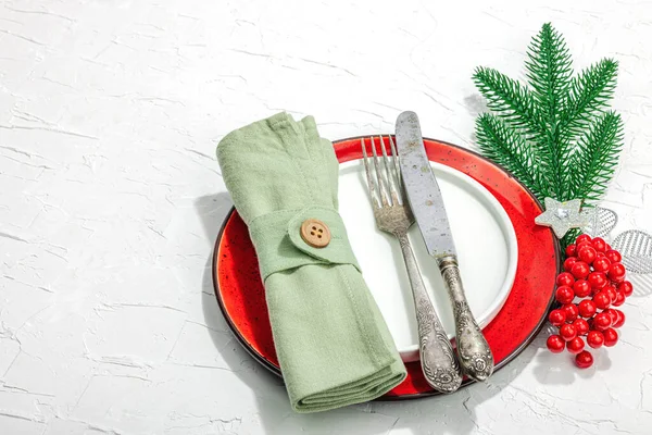 Christmas table setting. New Year cutlery, traditional winter decor, flat lay. Festive cozy mood, minimalist design. Hard light, dark shadow, white putty background, copy space