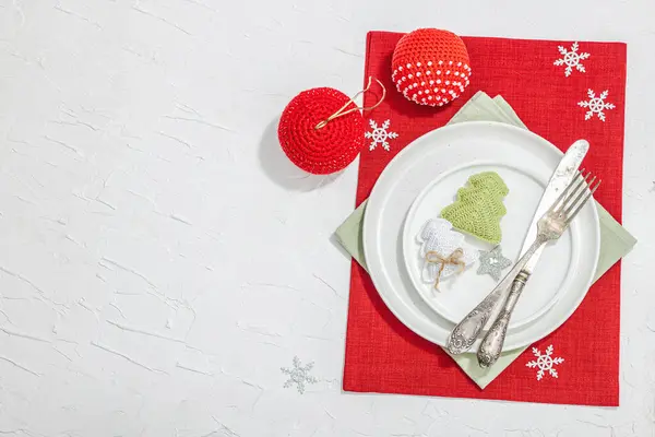 Christmas table setting. New Year cutlery, traditional winter decor, flat lay. Festive cozy mood, minimalist design. Hard light, dark shadow, white putty background, top view