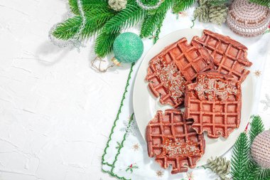 Çikolatalı Noel waffle 'ı. Yeni yıl kutlaması tatlısı, geleneksel düzenleme. Laktozsuz glüten pişirme, modaya uygun sert ışık, koyu gölge. Beyaz arkaplan, düz yatış, üst görünüm