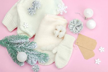 Sıcak kış kompozisyonu. Örgü eldivenler, sıcak eşarp, geleneksel Noel süsü, yeni yıl şenlik havası. Pembe zemin, düz yatış, üst görünüm