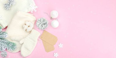 Sıcak kış kompozisyonu. Örgü eldivenler, sıcak eşarp, geleneksel Noel süsü, yeni yıl şenlik havası. Pembe arkaplan, düz yatış, pankart biçimi