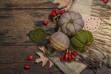Sonbahar konforlu kompozisyon. Tığ işi balkabakları, el yapımı, sonbahar hobisi. Dekorlar ve geleneksel dekorasyon, örgü. Sert ışık, karanlık gölge, eski ahşap arka plan, üst manzara.