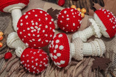 Sonbahar konforlu kompozisyon. Tığ işi manita mantarı, el yapımı, sonbahar hobisi. Dekorlar, geleneksel süslemeler, örgü örmeler. Sert ışık, karanlık gölge, eski ahşap arka plan, kapat