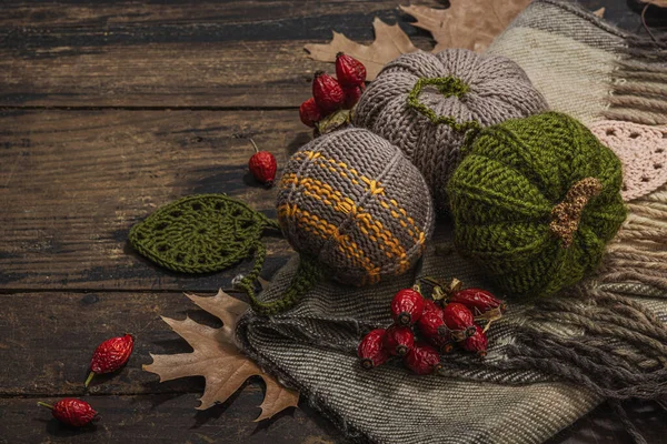 Autumn cozy mood composition. Crocheted pumpkins, handmade, fall hobby concept. Props and traditional decoration, knitting.Hard light, dark shadow, old wooden background, copy space