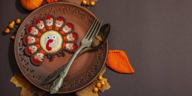 Sonbahar sofrası. Şükran Günü çatal bıçak takımı, geleneksel sonbahar dekorasyonu, düz yatış. Şenlik havası, el yapımı örgü örülmüş hindi ve yapraklar, kahverengi arka plan, afiş biçimi