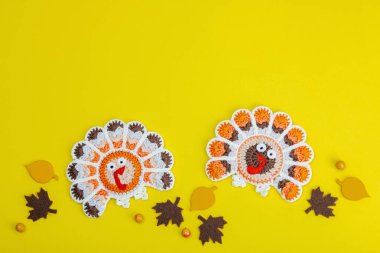 Sonbahar sofrası. Şükran Günü çatal bıçak takımı, geleneksel sonbahar dekorasyonu, düz yatış. Şenlik havası, el yapımı örülü hindi ve yapraklar, sarı arka plan, üst manzara