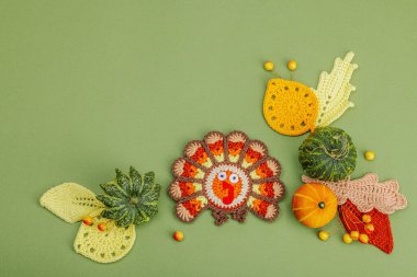 Sonbahar sofrası. Şükran Günü çatal bıçak takımı, geleneksel sonbahar dekorasyonu, düz yatış. Şenlikli bir ortam, el yapımı örülü hindi ve yapraklar, yeşil arka plan, üst manzara.