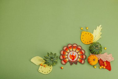 Sonbahar sofrası. Şükran Günü çatal bıçak takımı, geleneksel sonbahar dekorasyonu, düz yatış. Şenlikli bir ortam, el yapımı örülü hindi ve yapraklar, yeşil arka plan, üst manzara.