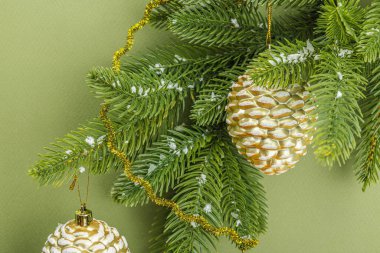 Geleneksel yeni yıl kompozisyonu. Şenlikli dekor, karlı Noel ağacı dalları, balolar, altın çiçekler. Savannah Green renk arkaplanı, düz uzanma, metin için yer