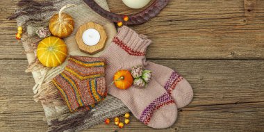 Sonbahar kompozisyonu. Atkı, sıcak örgü çorap, mum, balkabağı, sonbahar dekoru. Ahşap kırsal arkaplan, pankart biçimi