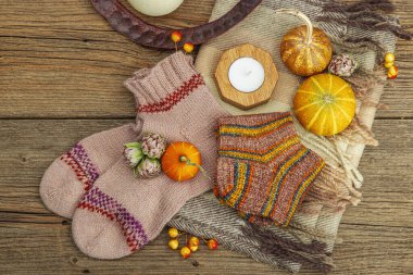 Sonbahar kompozisyonu. Atkı, sıcak örgü çorap, mum, balkabağı, sonbahar dekoru. Ahşap kırsal arkaplan, üst manzara