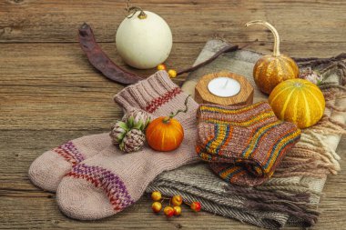 Sonbahar kompozisyonu. Atkı, sıcak örgü çorap, mum, balkabağı, sonbahar dekoru. Ahşap kırsal arkaplan, alanı kopyala
