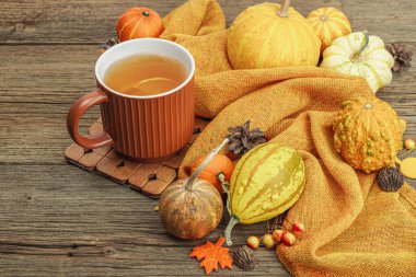 Baharatlı sıcak çay. Sonbahar neşesi, geleneksel sonbahar içeceği. Balkabağı, eşarp, yapraklar, kozalaklar. Tahta kaplama arka plan, kopyalama alanı