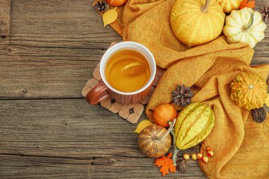 Baharatlı sıcak çay. Sonbahar neşesi, geleneksel sonbahar içeceği. Balkabağı, eşarp, yapraklar, kozalaklar. Tahta kaplama arka plan, üst görünüm