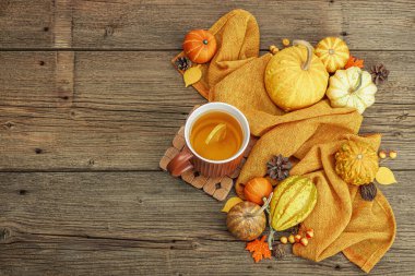 Baharatlı sıcak çay. Sonbahar neşesi, geleneksel sonbahar içeceği. Balkabağı, eşarp, yapraklar, kozalaklar. Tahta kaplama arka plan, üst görünüm