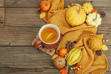 Baharatlı sıcak çay. Sonbahar neşesi, geleneksel sonbahar içeceği. Balkabağı, eşarp, yapraklar, kozalaklar. Tahta kaplama arka plan, üst görünüm