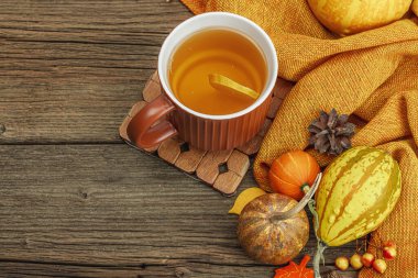 Baharatlı sıcak çay. Sonbahar neşesi, geleneksel sonbahar içeceği. Balkabağı, eşarp, yapraklar, kozalaklar. Tahta kaplama arka plan, üst görünüm