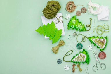 Geleneksel Yeni Yıl kompozisyonu. Şenlikli el yapımı dekor, Noel ağaçlarının haçla süslendiğini hissetti. Tatil zamanı konsepti, açık yeşil arkaplan, üst görünüm