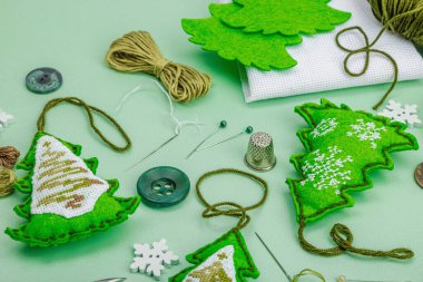 Geleneksel Yeni Yıl kompozisyonu. Şenlikli el yapımı dekor, Noel ağaçlarının haçla süslendiğini hissetti. Tatil zamanı konsepti, açık yeşil arkaplan, kapat