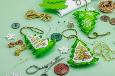 Geleneksel Yeni Yıl kompozisyonu. Şenlikli el yapımı dekor, Noel ağaçlarının haçla süslendiğini hissetti. Tatil zamanı konsepti, açık yeşil arkaplan, kapat