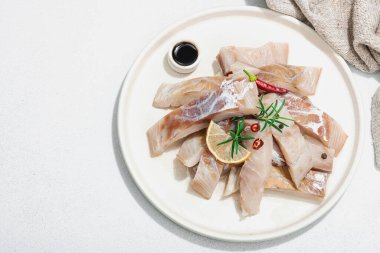 Çiğ pollock (Pollachius virens) fileto. Sağlıklı yaşam tarzı için taze balık. Limon, biberiye, deniz tuzu, kırmızı biber, karabiber. Hafif taş zemin, düz zemin, üst manzara