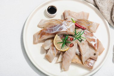 Çiğ pollock (Pollachius virens) fileto. Sağlıklı yaşam tarzı için taze balık. Limon, biberiye, deniz tuzu, kırmızı biber, karabiber. Hafif taş zemin, düz zemin, üst manzara