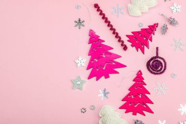 Geleneksel yeni yıl kompozisyonu pembe renkli. Şölen dekoru, el yapımı Noel ağaçları, şenlikli dekorlar, kar taneleri. Pastel arkaplan, düz yatak, üst görünüm