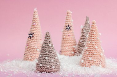 El yapımı kış kompozisyonu. Tığ işi Noel ağaçları, pembe arka planda yapay kar. Yaratıcı hobi konsepti, üst görünüm