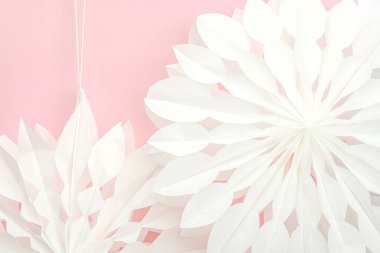 Geleneksel kağıt 3D kar taneleri, pastel pembe arka planda. Kış el yapımı, DIY etkinliği. Noel tatili için evi dekore etmenin temel unsurları. Metin için yer