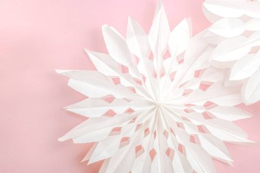 Geleneksel kağıt 3D kar taneleri, pastel pembe arka planda. Kış el yapımı, DIY etkinliği. Noel tatili için evi dekore etmenin temel unsurları. Metin için yer