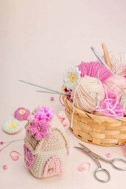 El yapımı bahar dekoru konsepti. Yaratıcı tığ işi, ev figürleri, geleneksel çiçekler ve kalpler. Kutlama kartı, yumuşak pastel kayısı arka planı, kopyalama alanı.