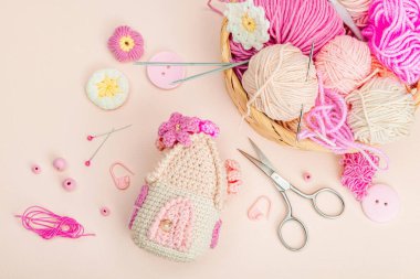 El yapımı bahar dekoru konsepti. Yaratıcı tığ işi, ev figürleri, geleneksel çiçekler ve kalpler. Kutlama kartı, yumuşak pastel kayısı arkaplan, üst manzara.