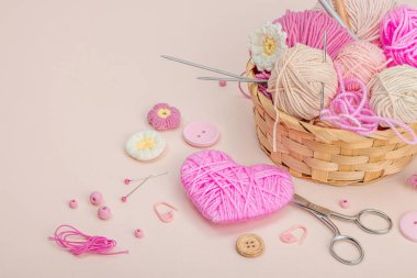 El yapımı bahar dekoru konsepti. Yaratıcı tığ işi, geleneksel çiçekler ve pembe bir kalp. Kutlama kartı, yumuşak pastel kayısı arka planı, kopyalama alanı.