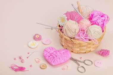 El yapımı bahar dekoru konsepti. Yaratıcı tığ işi, geleneksel çiçekler ve pembe bir kalp. Kutlama kartı, yumuşak pastel kayısı arka planı, kopyalama alanı.