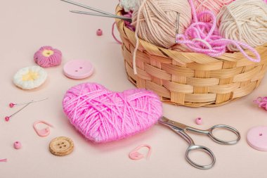 El yapımı bahar dekoru konsepti. Yaratıcı tığ işi, geleneksel çiçekler ve pembe bir kalp. Kutlama kartı, yumuşak pastel kayısı arkaplanı, yakın çekim.