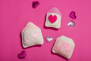 El yapımı sevgililer günü konsepti. Yaratıcı ev figürleri, geleneksel kalpler, bahar tığ işi. Kutlama kartı, eflatun arkaplan, sert ışık, koyu gölge, düz yatak, üst görünüm