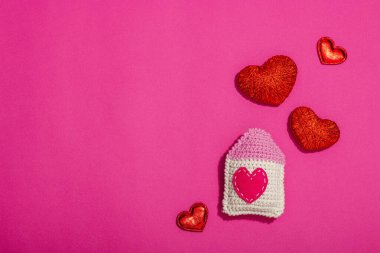 El yapımı sevgililer günü konsepti. Yaratıcı ev figürleri, geleneksel kalpler, bahar tığ işi. Kutlama kartı, eflatun arkaplan, sert ışık, koyu gölge, düz yatak, üst görünüm