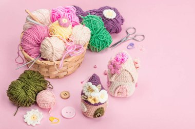 El yapımı bahar dekoru konsepti. Yaratıcı tığ işi, ev figürleri, geleneksel çiçekler falan. Kutlama kartı, yumuşak pastel pembe arka plan, kopyalama alanı.